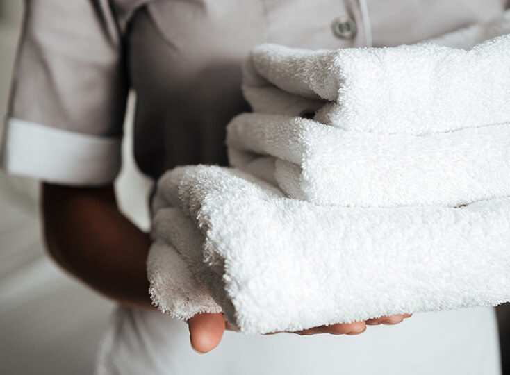 Staff member holding a stack of clean white towels in a senior living community.