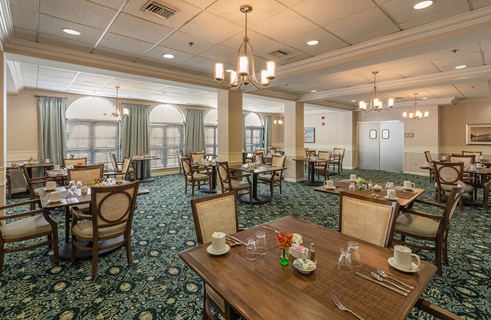 Spacious dining room with arranged tables in a senior living community.