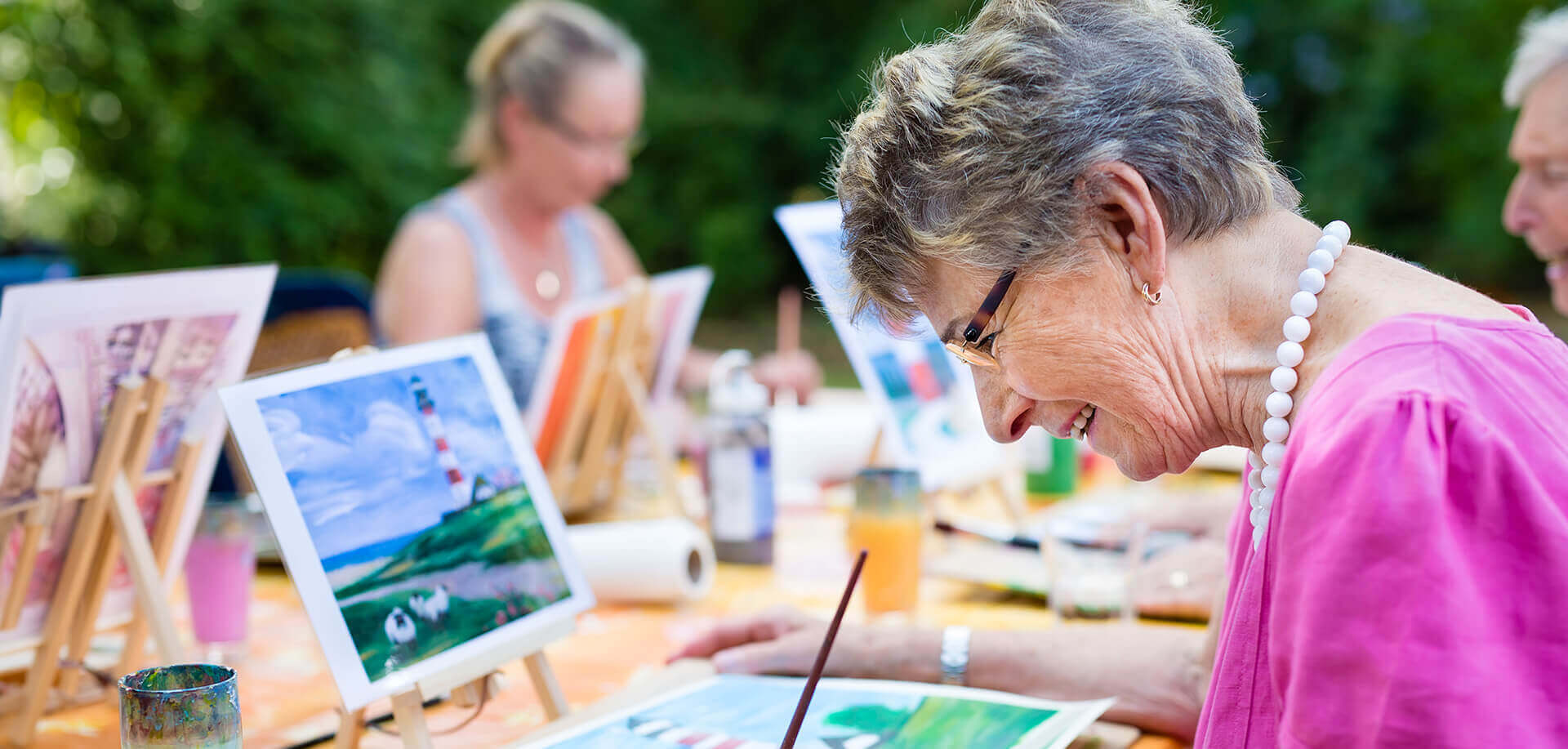 Elderly residents participating in an outdoor painting class activity.