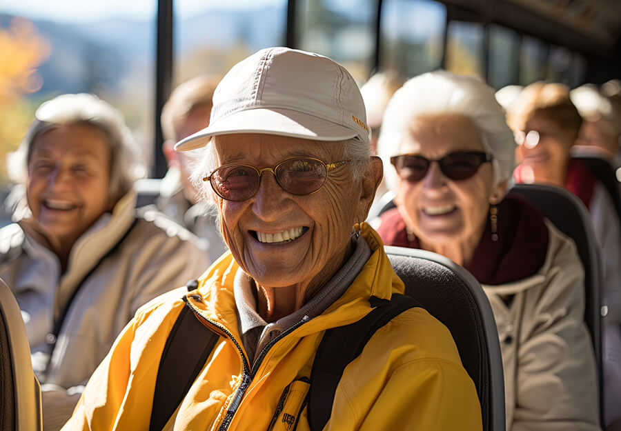 Seniors on a bus trip, smiling and enjoying a scenic outing from their senior living community.