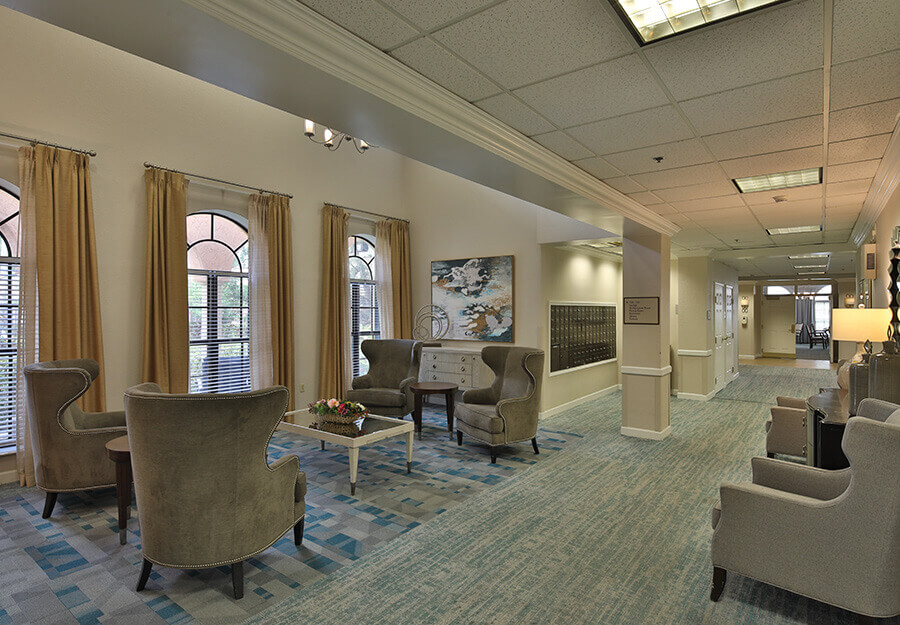 Lounge area with armchairs, coffee table, and decor in senior living community common space.