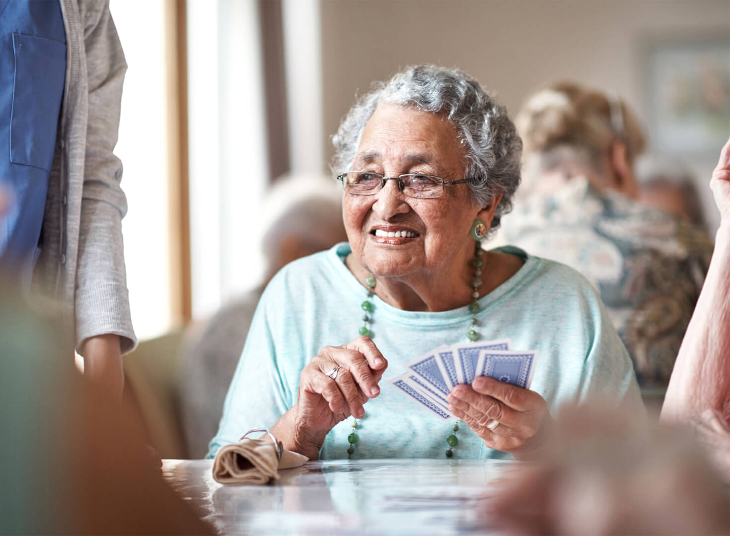 Senior woman enjoying a card game in community area with other residents.