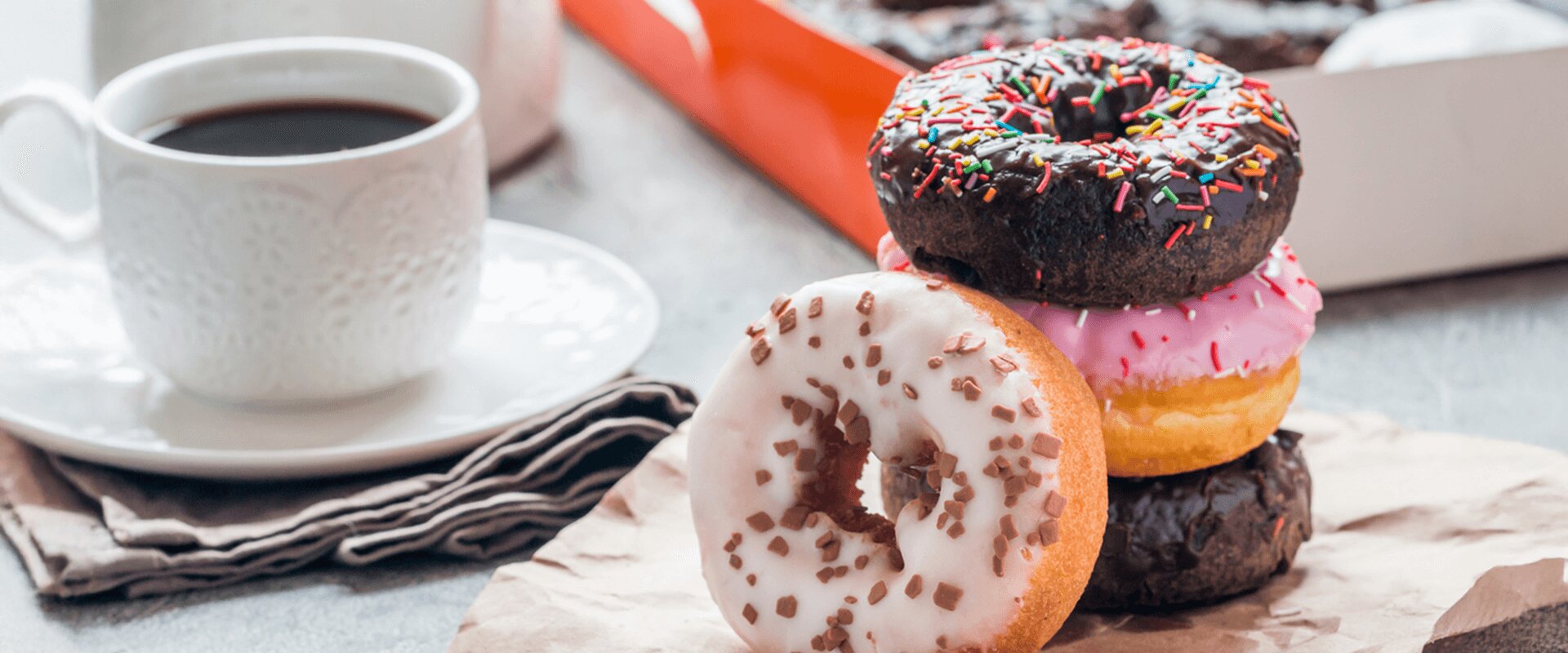 Stacked doughnuts of various flavors and a mug of coffee