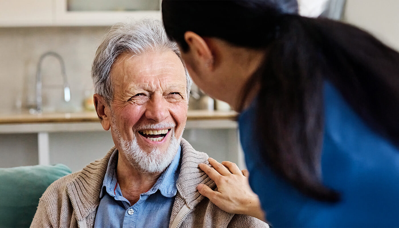 Senior man smiles at female caregiver